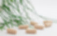 Private label supplement capsules in a clear jar next to a plant.